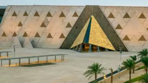 Grand Egyptian Museum exterior featuring the golden pyramid design and unique geometric patterns during a scenic sunset.