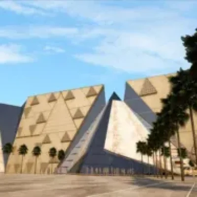 Grand Egyptian Museum facade featuring modern pyramidal architecture and palm trees under a blue sky in Giza.