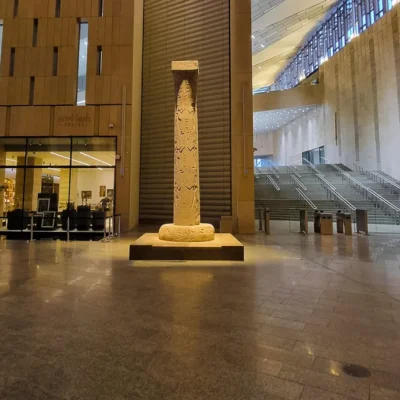 Alt Text: The Hanging Obelisk of King Ramses II at the Grand Egyptian Museum entrance, showcasing ancient carvings and modern design.